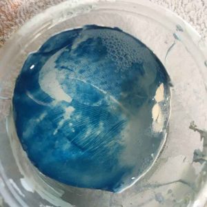cyanotype eggshell sitting in a vinegar bath